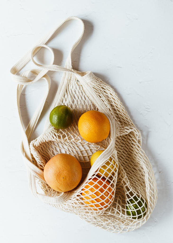 Assorted citrus fruits in cotton sack on white surface