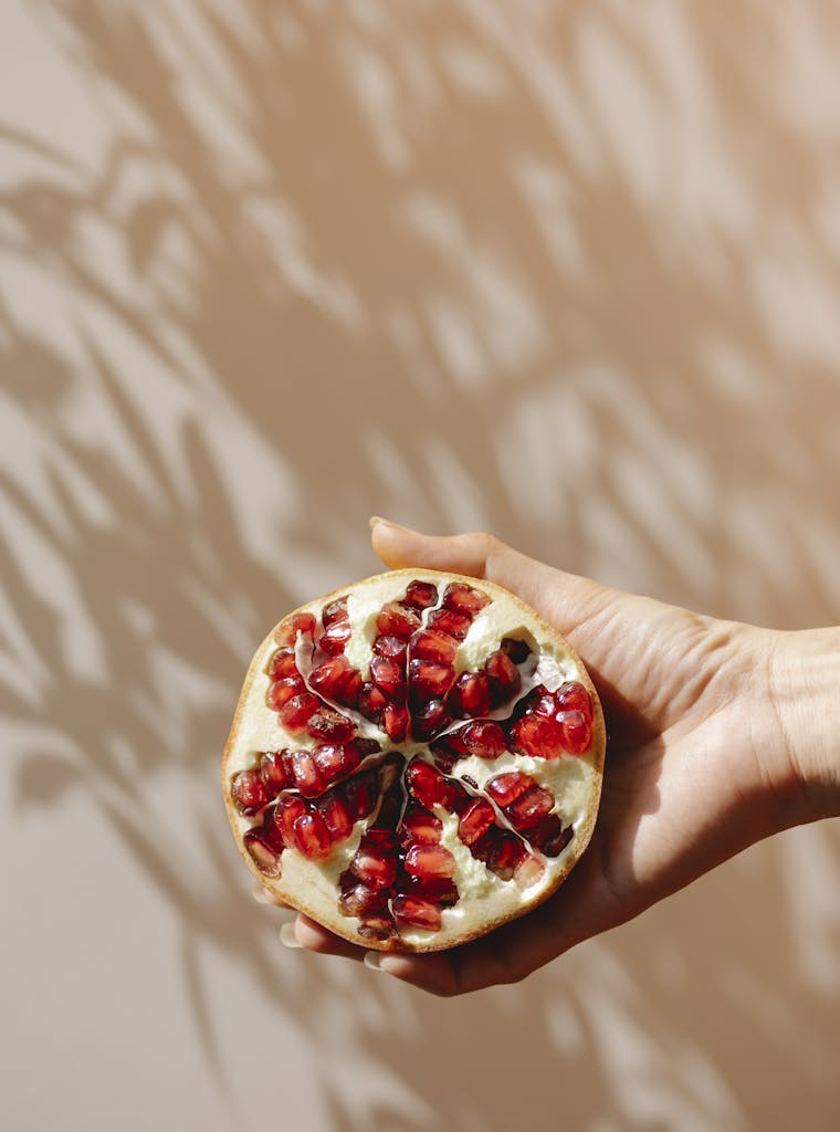 Crop woman demonstrating ripe pomegranate